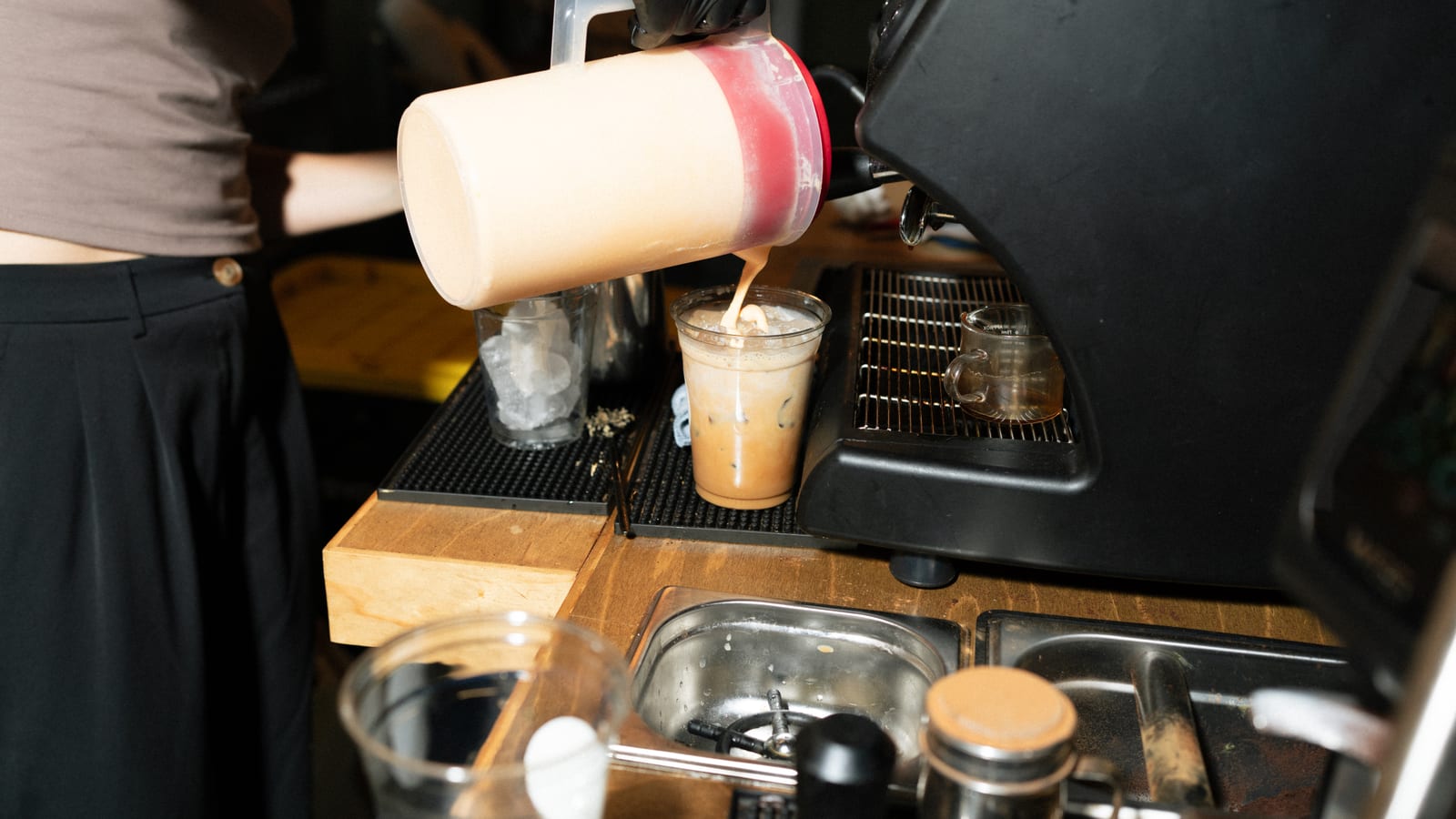 The barista pouring the first iced latte of the morning
