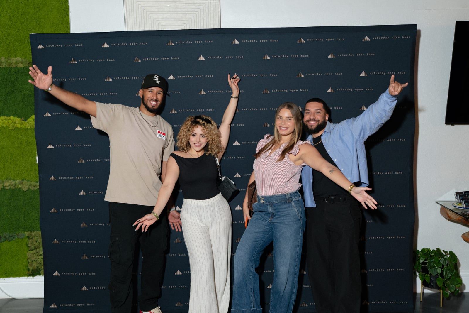Four guests with their arms out at the Saturday Open Haus wall
